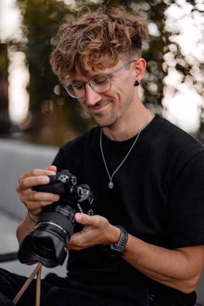Matthias holding his Fujifilm camera while smiling at work.